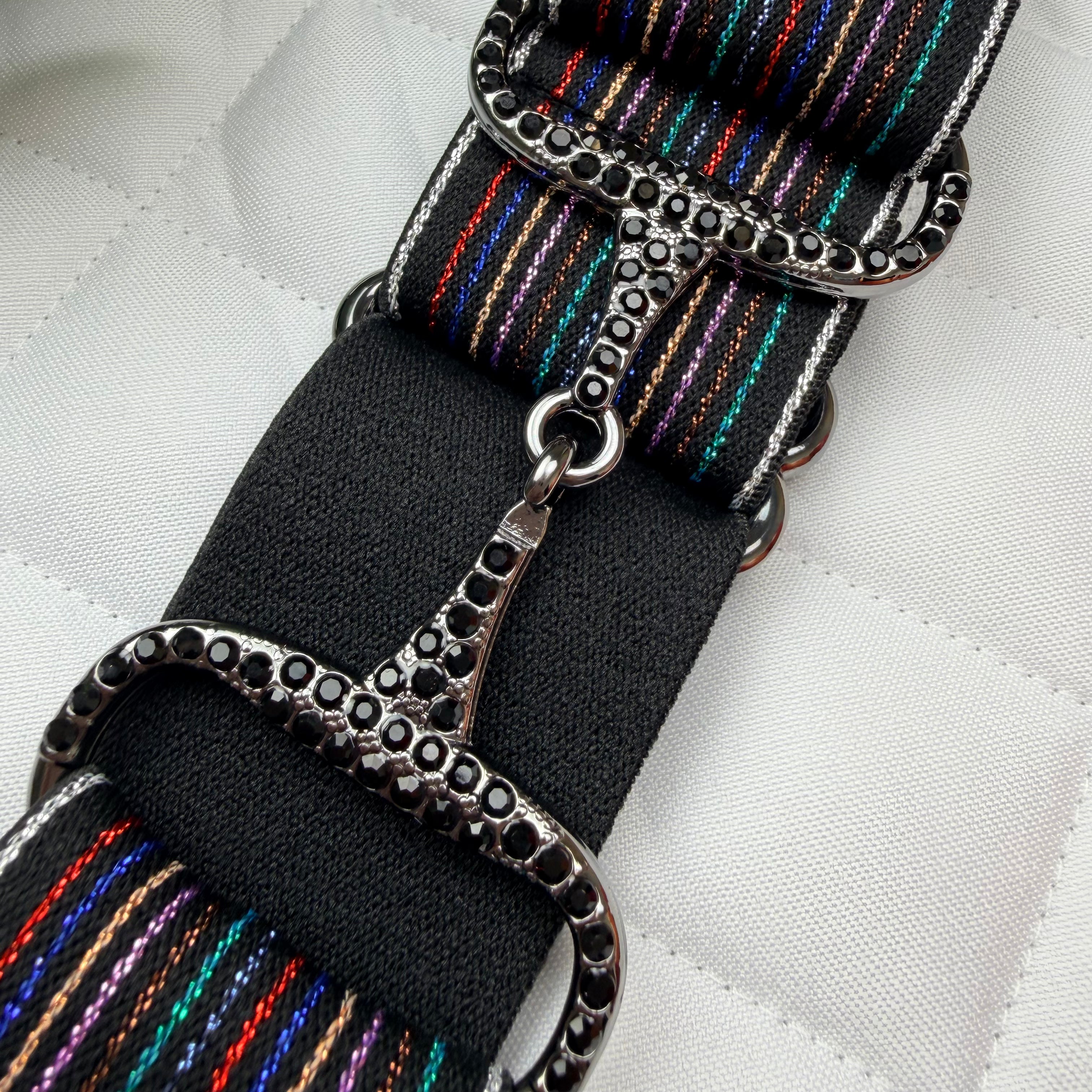 Black rainbow belt with rhinestone buckle on white saddle pad
